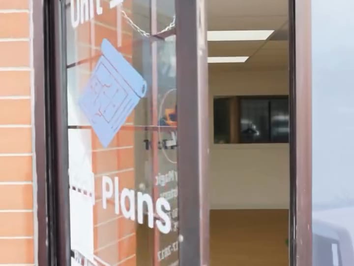 The glass door of Unit 105 marked 1to1 Plans, by appointment only
